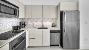 Una cocina moderna con electrodomésticos de acero inoxidable, salpicadero de azulejos y armarios de tonos claros.