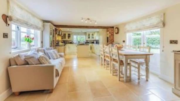 A spacious living room with a sofa, a dining table with chairs, and a kitchen in the background.