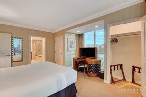 A hotel room with a large bed, a desk with a computer, a TV, and a wardrobe.