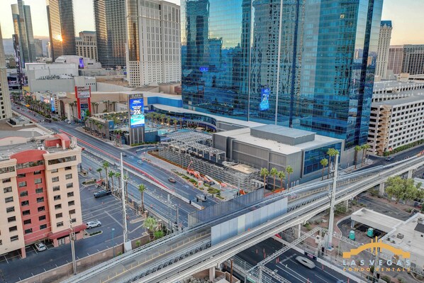 Un área urbana de varios niveles con edificios modernos, un llamativo rascacielos de cristal y una intrincada red de carreteras que incluye vías elevadas.