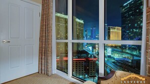 A room with a large window offering a nighttime city view, a white door, and a patterned curtain. - MGM Signature-Full Kitchen F1 Strip View 1BR (Las Vegas)