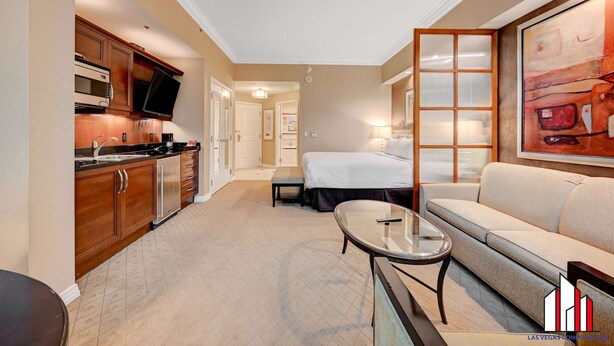 Une chambre d’hôtel équipée d’un coin cuisine, d’un lit, d’un canapé, d’une petite table et d’un tableau au mur.