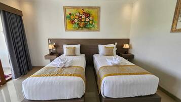 Habitación de hotel con dos camas, un cuadro de flores en la pared y vista al mar.