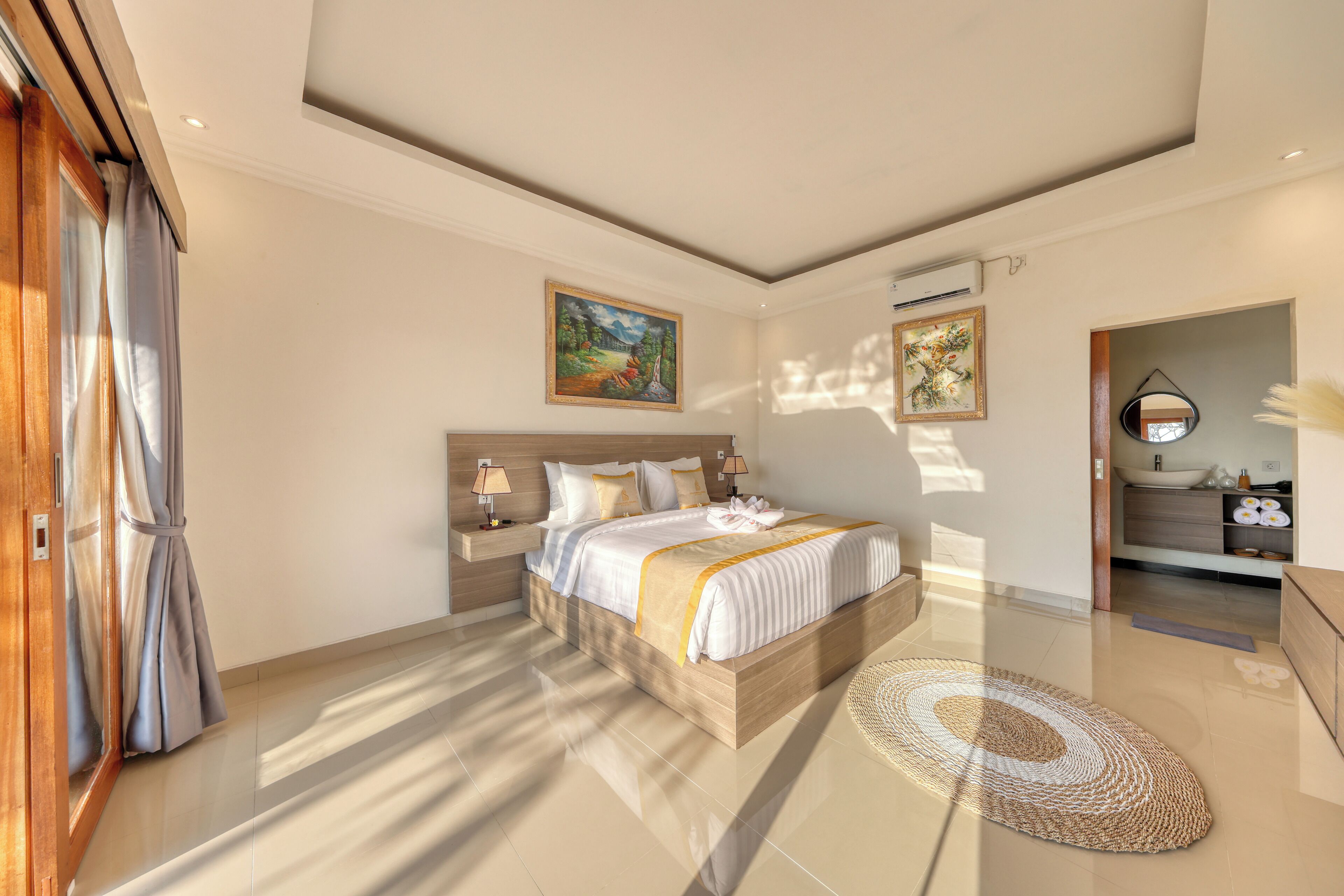 A modern bedroom with a large bed, bedside tables, a mirror, and artwork on the walls.