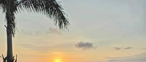 A sunset view from a balcony with a drink in a glass.