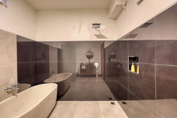 Un baño moderno con una bañera independiente, un espejo grande y una zona de ducha.