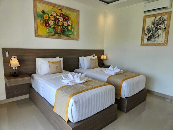 Ein Hotelzimmer mit zwei Betten, einem großen Blumenbild über den Betten und einem kleineren Kunstwerk an der Wand.