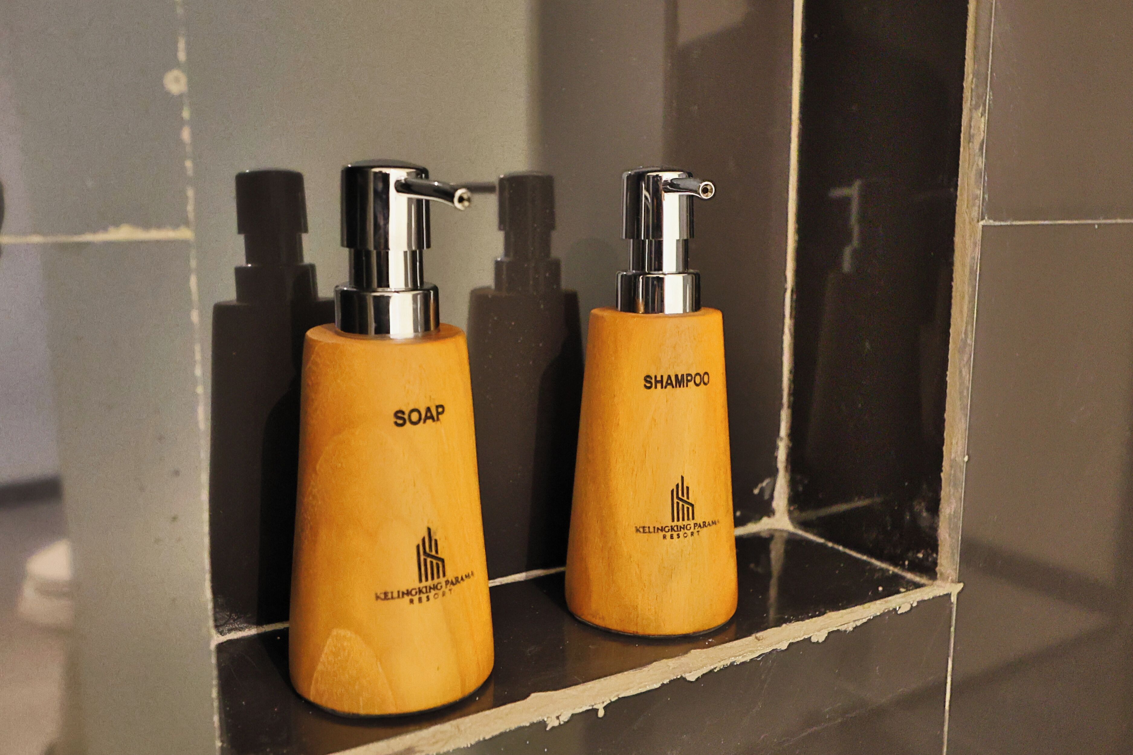 Two wooden bottles of soap and shampoo with a pump dispenser, labeled 'Kelingking Paramarshi Resort'.