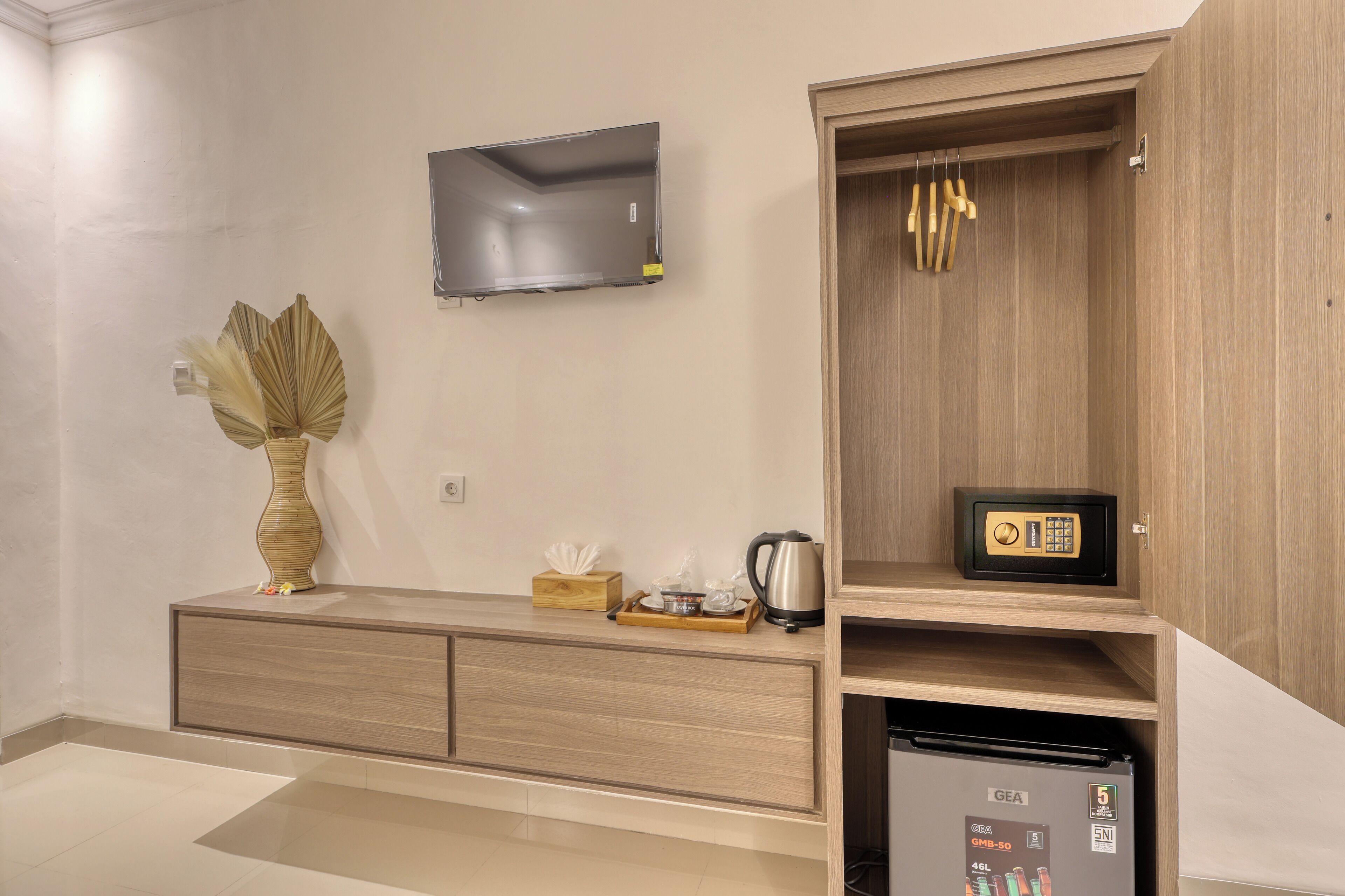 Una cocina moderna con microondas integrado, un mueble de madera con caja fuerte y un refrigerador pequeño.