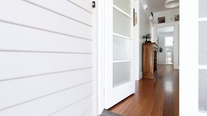 A hallway with white siding, a wooden floor, and a wooden cabinet. - The Basin Cottage - Closest Home to The Gorge (West Launceston)
