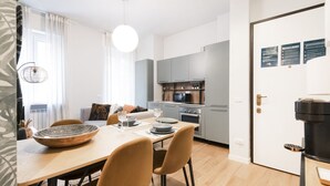 Una cocina moderna con armarios grises, una mesa de comedor con sillas y una cafetera.