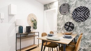Un comedor con una mesa de madera, cuatro sillas, una cafetera, una planta y decoración en la pared.