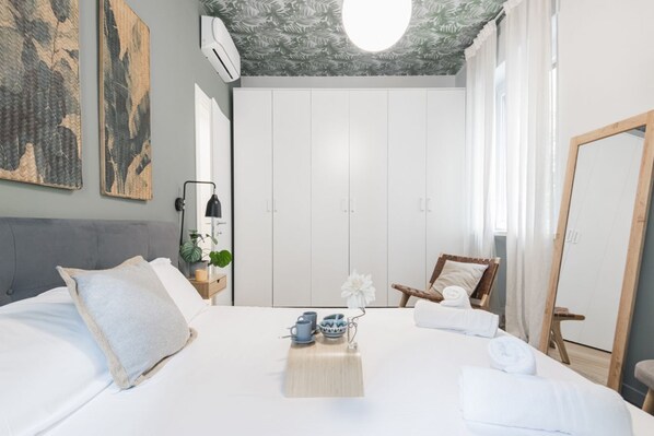 A bedroom with a bed, a chair, a wardrobe, and a mirror.