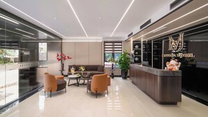 A modern hotel lobby with a reception desk, seating area, and a large window. - Marina Hotel (Bac Giang)
