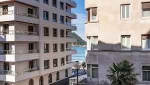 A multi-story hotel with balconies and a view of the sea.