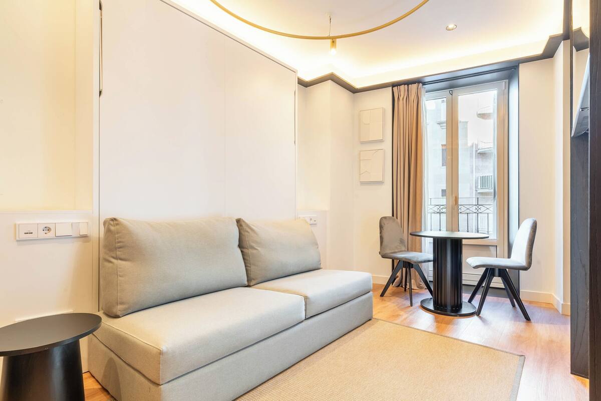 Un salon moderne avec un canapé, une petite table ronde et deux chaises.