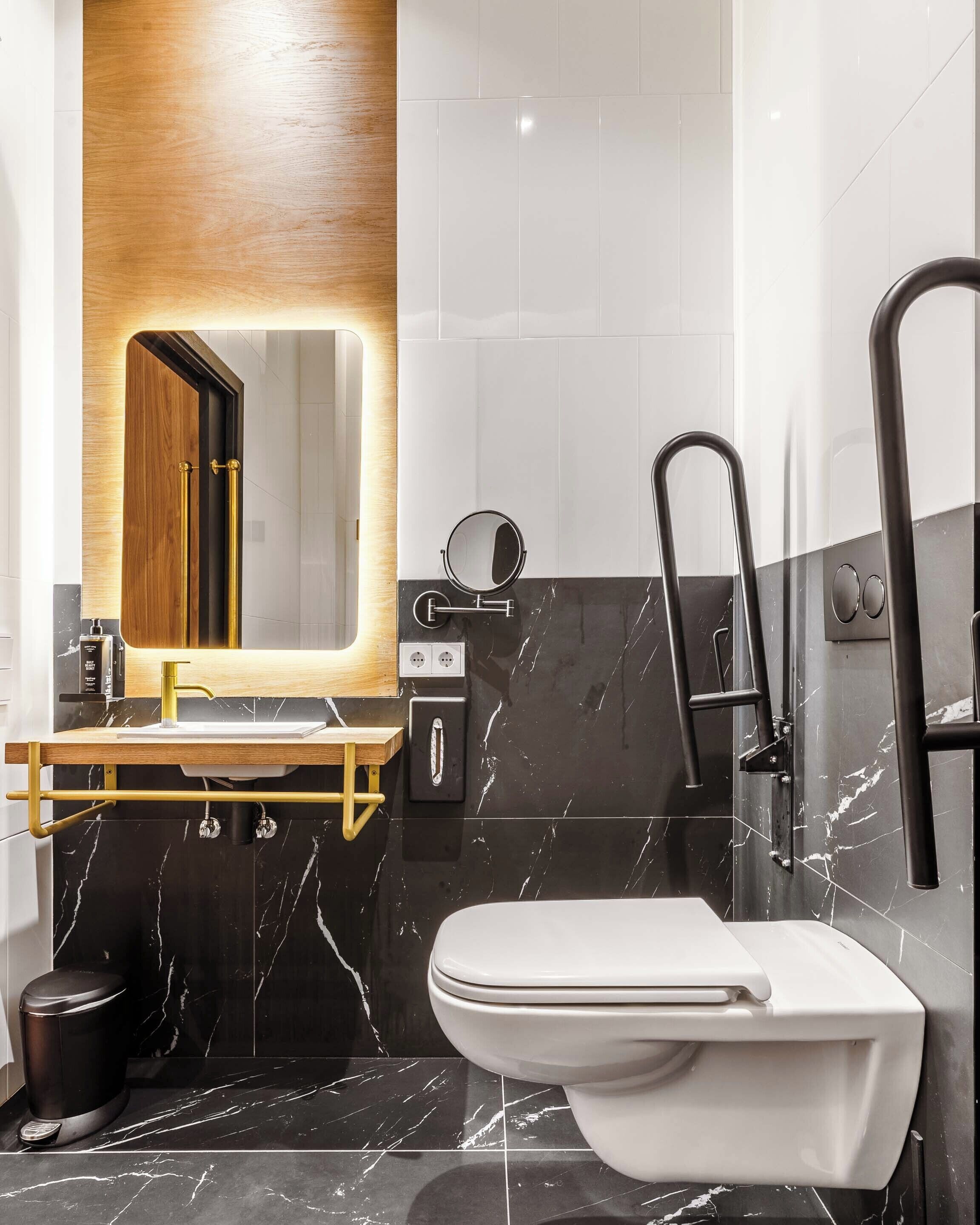 Een moderne badkamer met een houten wastafelmeubel, een zwart marmeren wastafel, een wit toilet en een zwart bad.