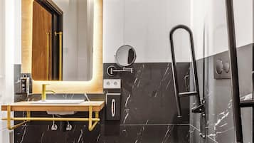 Een moderne badkamer met een houten wastafelmeubel, een zwart marmeren wastafel, een wit toilet en een zwart bad.