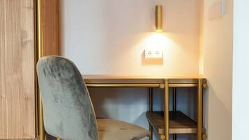 A modern desk with a chair, a wall-mounted light, and a power outlet.
