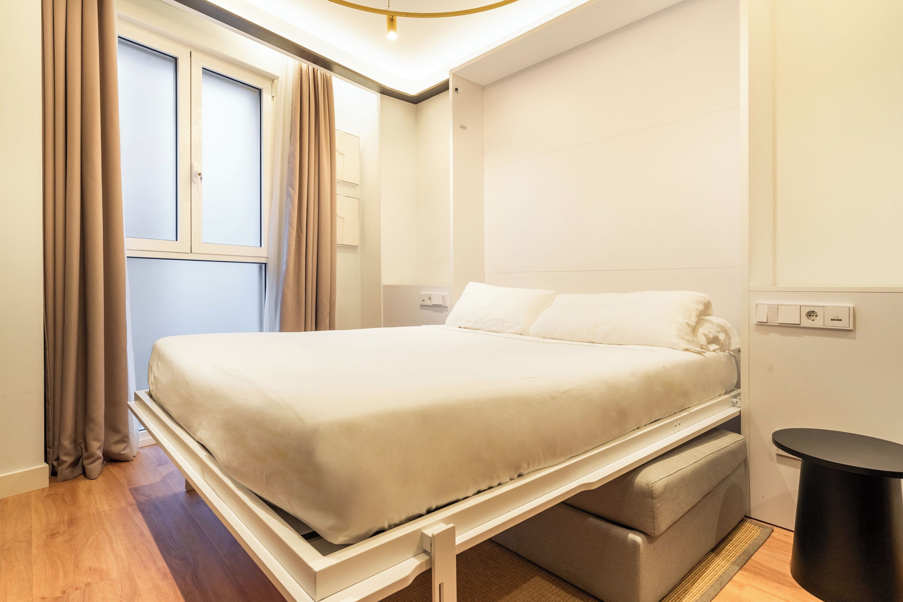 Un dormitorio ordenado con cama, mesita de noche y un pequeño armario.