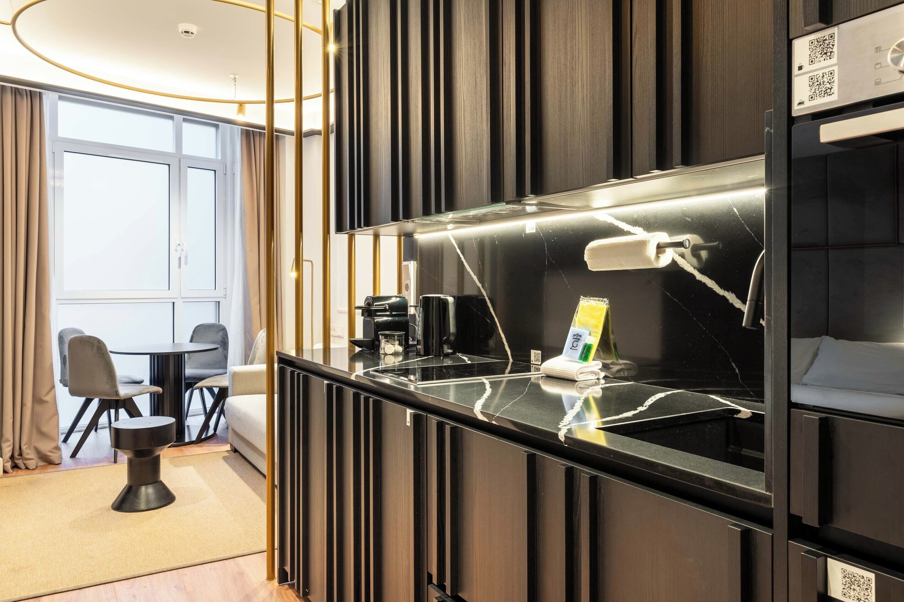 Ein modernes Hotelzimmer mit einer schwarzen Marmorplatte, einer Kaffeemaschine und einem kleinen Tisch mit Stühlen.