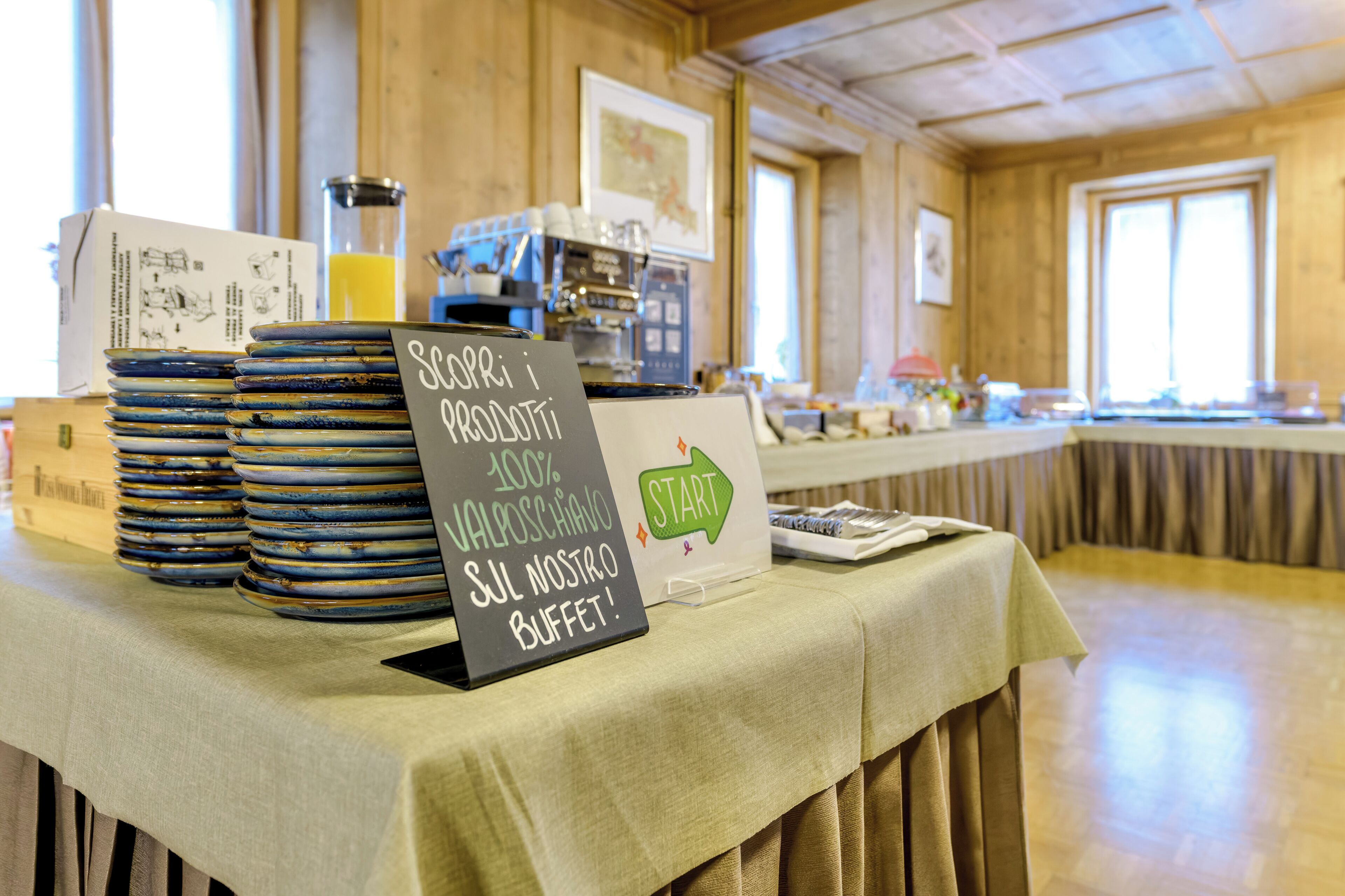 A buffet setup with plates, a coffee machine, and a sign indicating a 100% local product buffet.