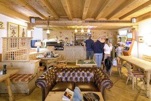 Een gezellige barruimte met houten meubels, een bar en een zithoek met een leren bank.