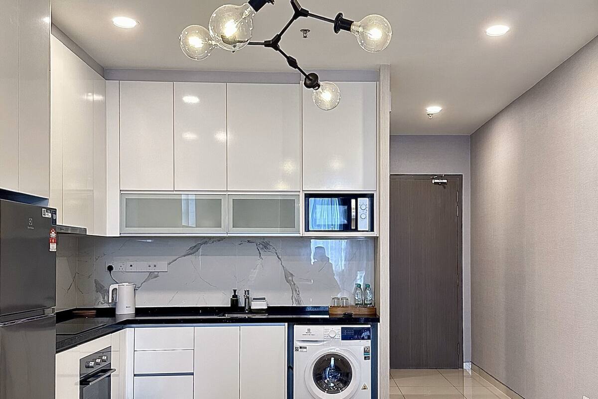 A modern kitchen with white cabinets, a glass-top dining table, and a unique light fixture.