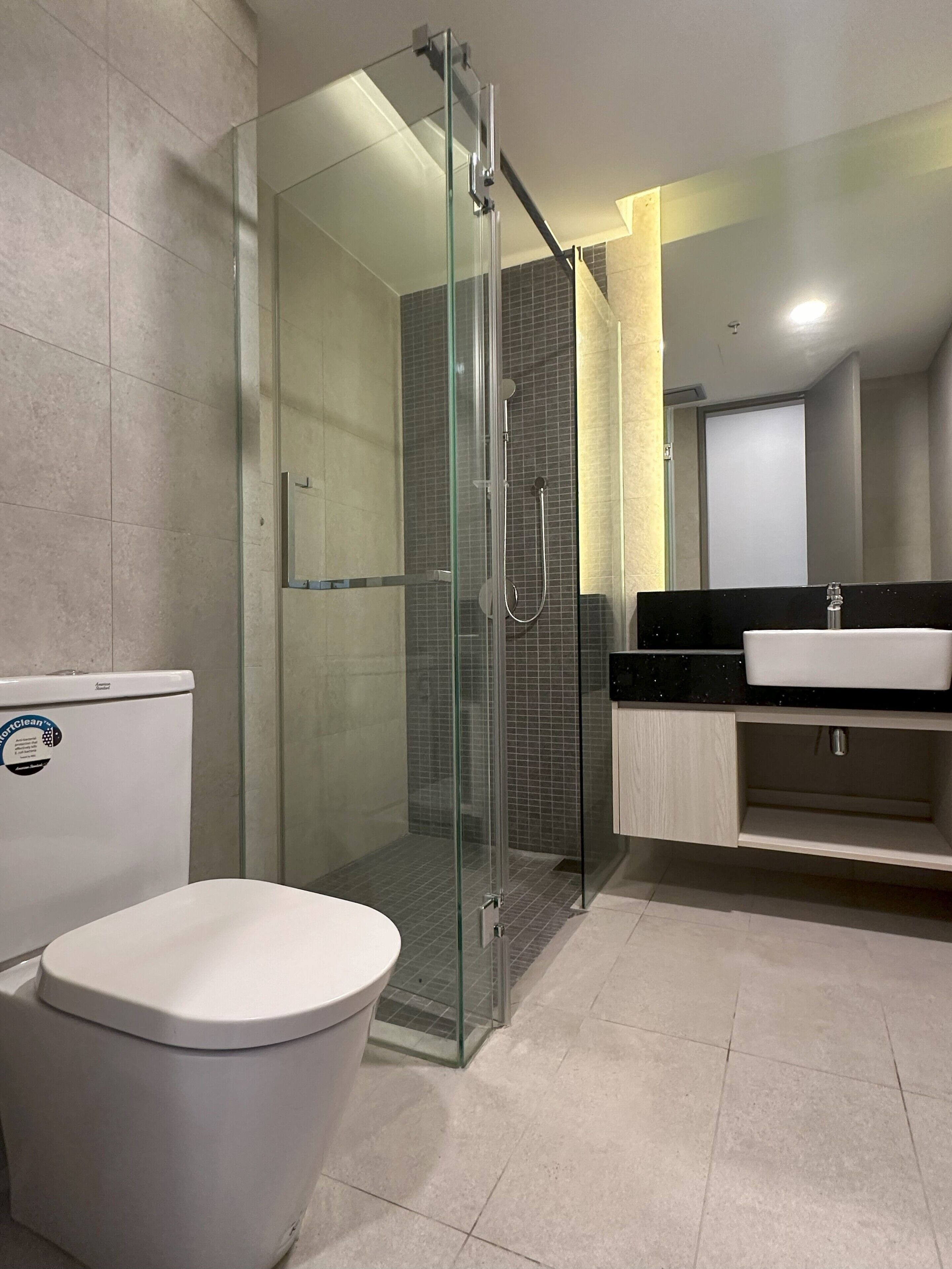 A modern bathroom with a glass-enclosed shower, a white toilet, and a black countertop with a sink.