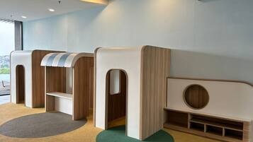 Zona infantil con juegos blandos y vistas al exterior.