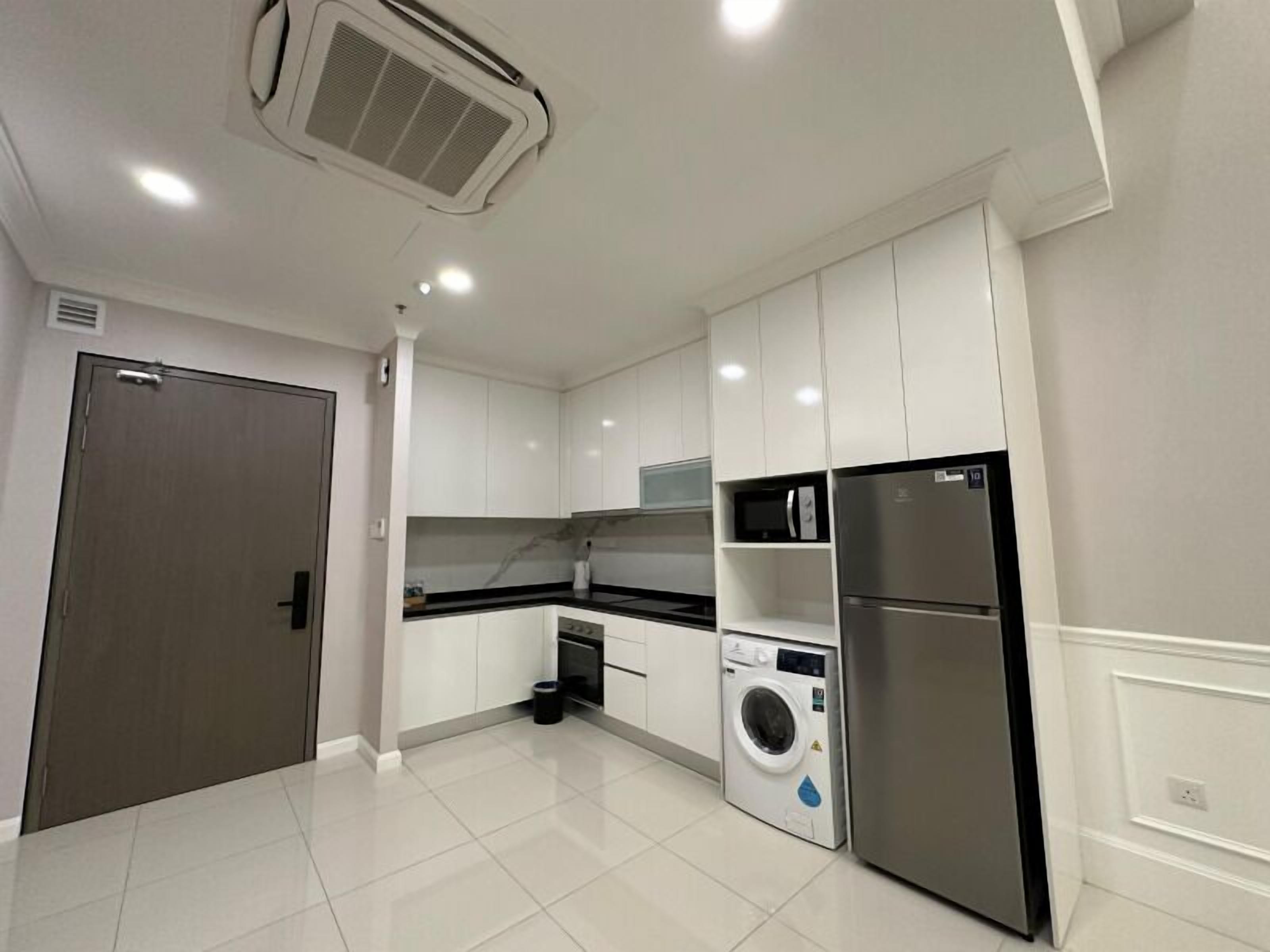 A modern kitchen with white cabinets, a built-in microwave, a stainless steel refrigerator, and a washing machine.
