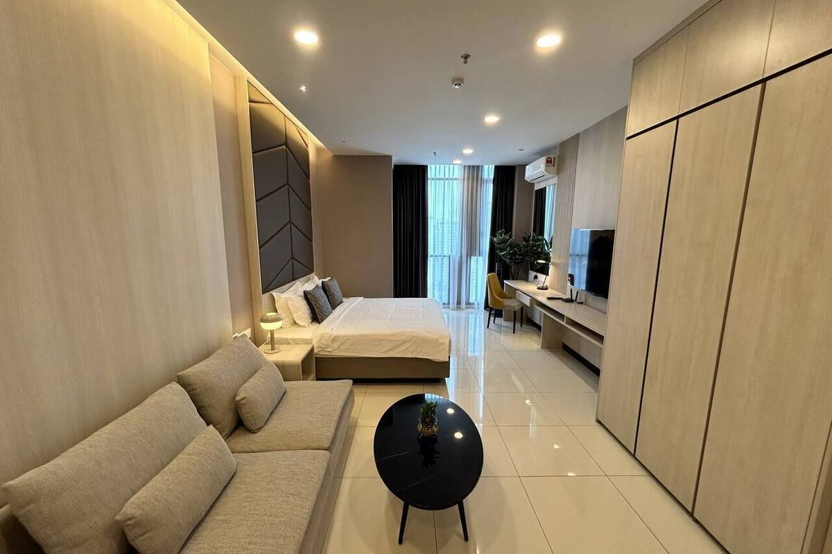 A modern hotel room with a bed, sofa, and a small round table.