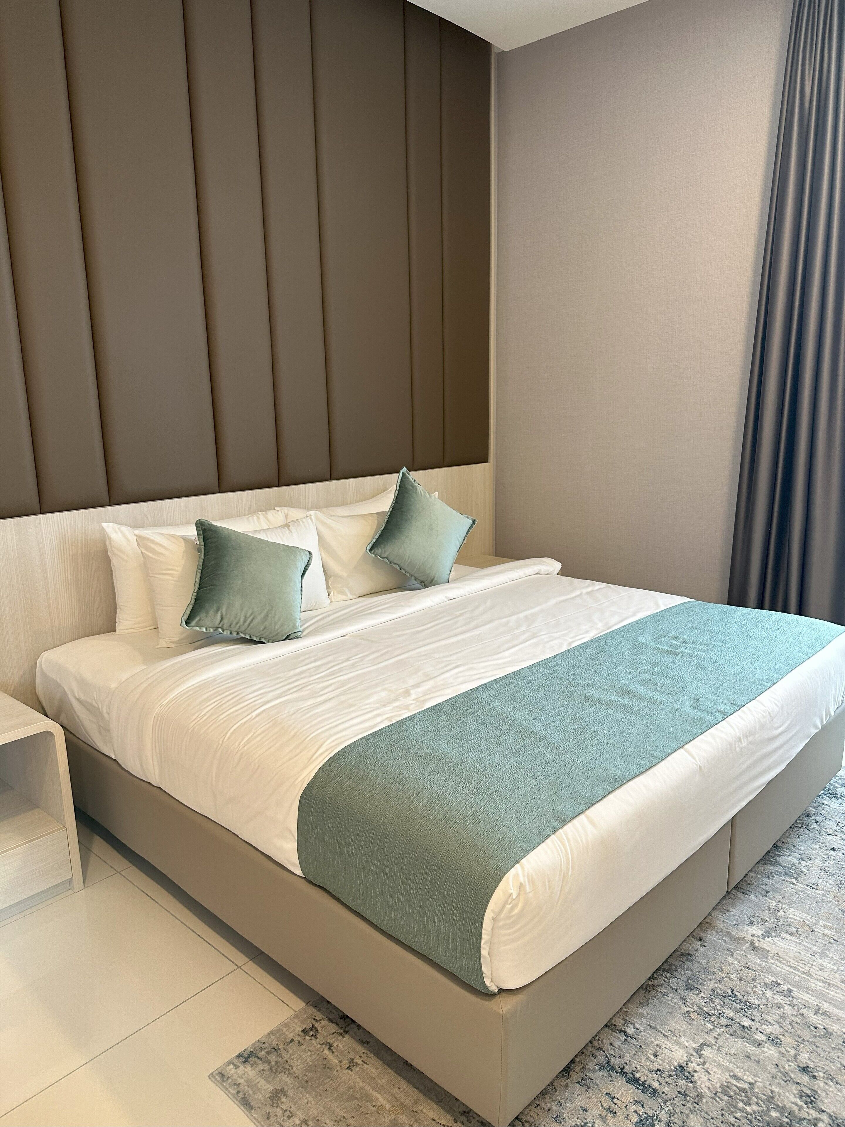 A modern bedroom with a large bed, a nightstand, and a headboard with vertical panels.
