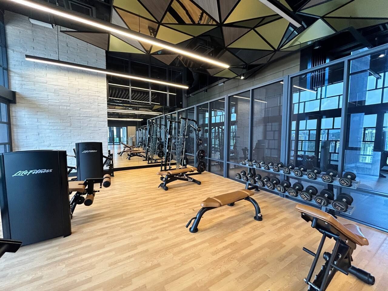A gym with exercise equipment, benches, and a mirrored wall.