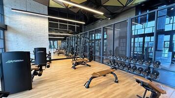 A gym with exercise equipment, benches, and a mirrored wall.