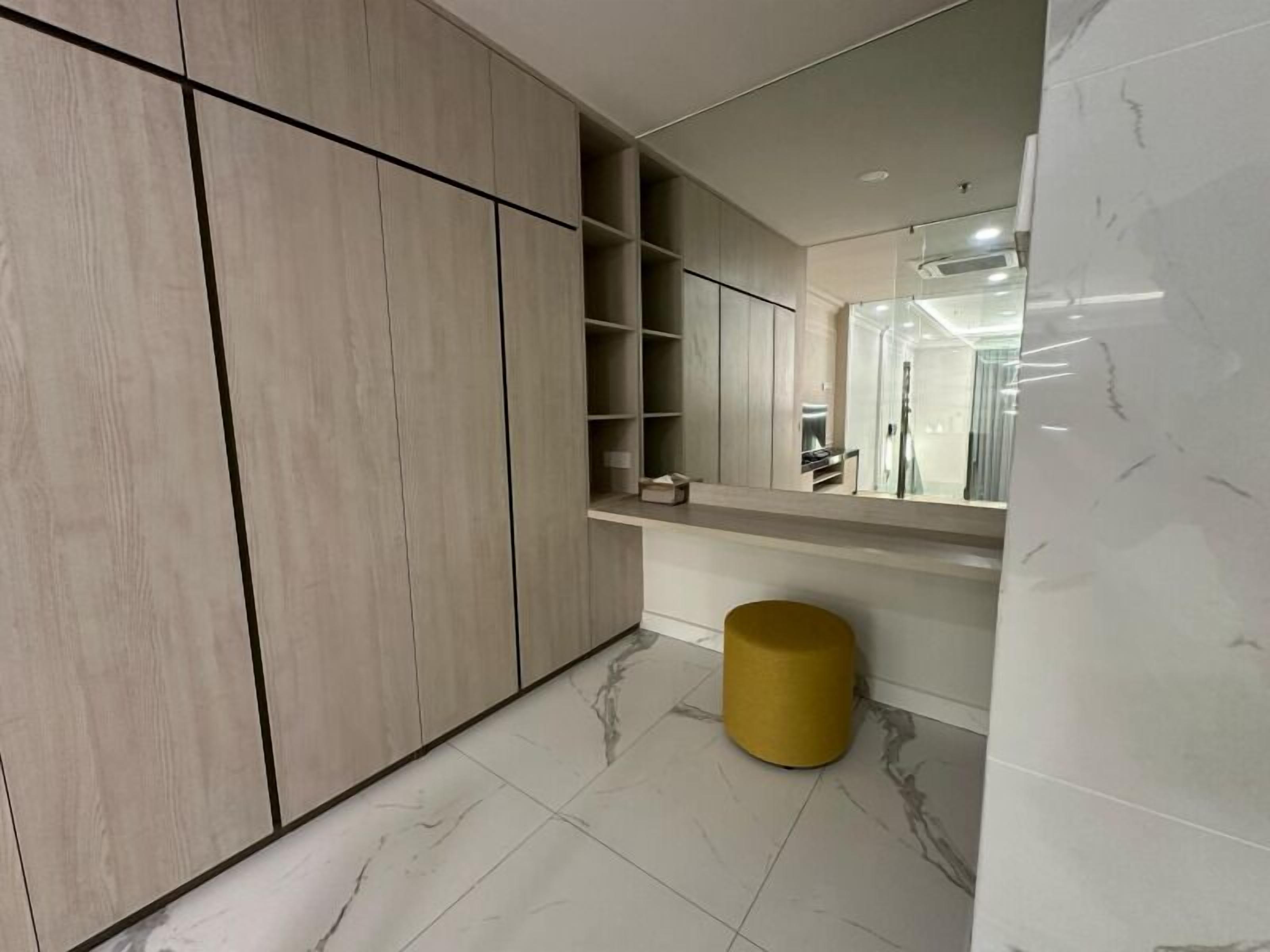 Un baño moderno con un espejo grande, armarios de madera y piso de mármol.