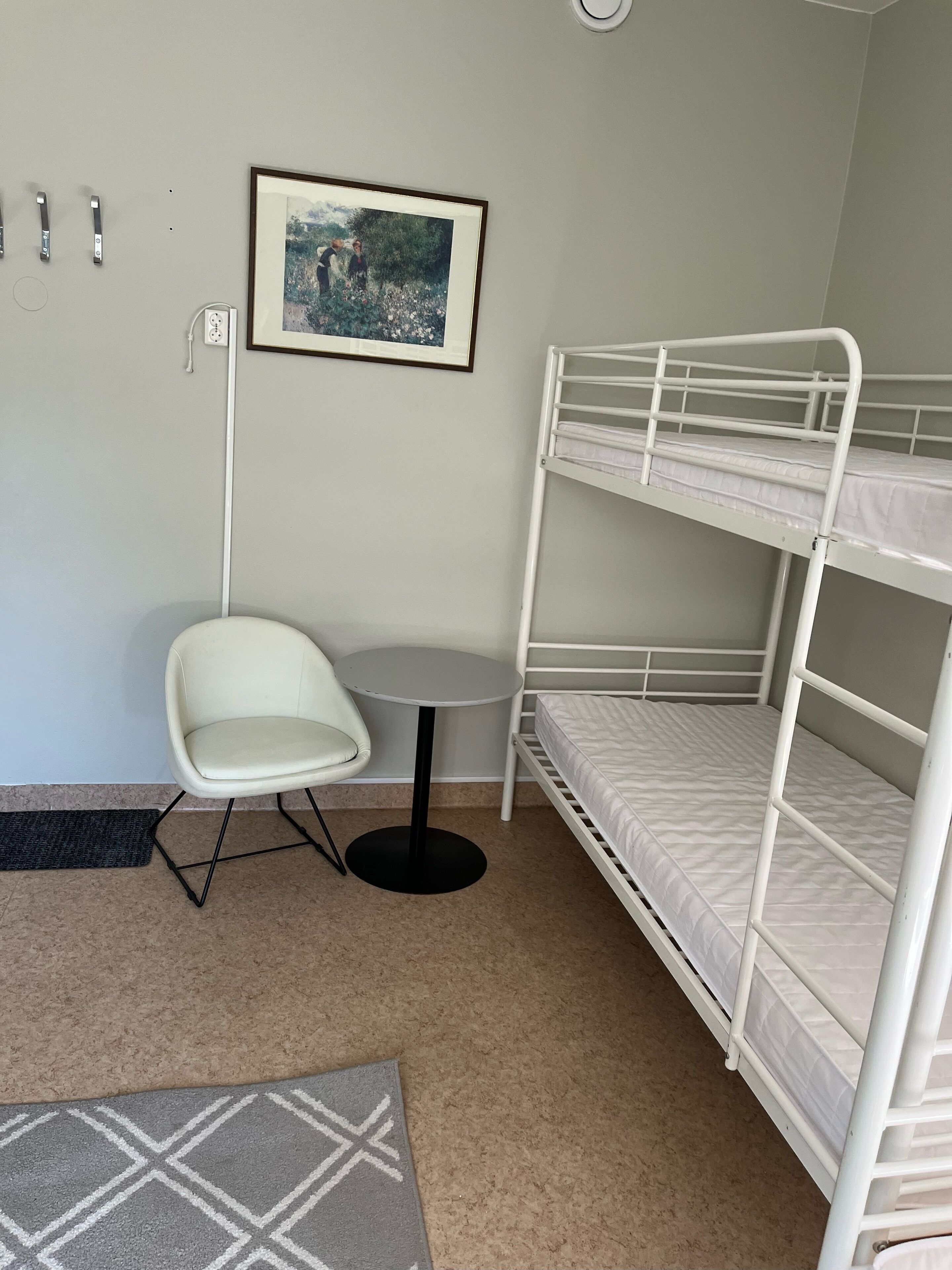 A bunk bed room with a small round table and a chair. There is a framed picture on the wall.