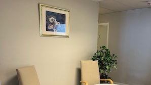 Un salón de conferencias con dos sillas, una mesa y un cuadro en la pared.
