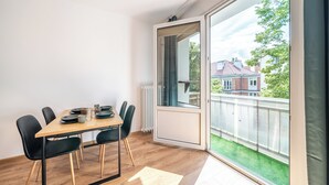 Spiseområde med et træbord, sorte stole og udsigt over et boligområde gennem et stort vindue.