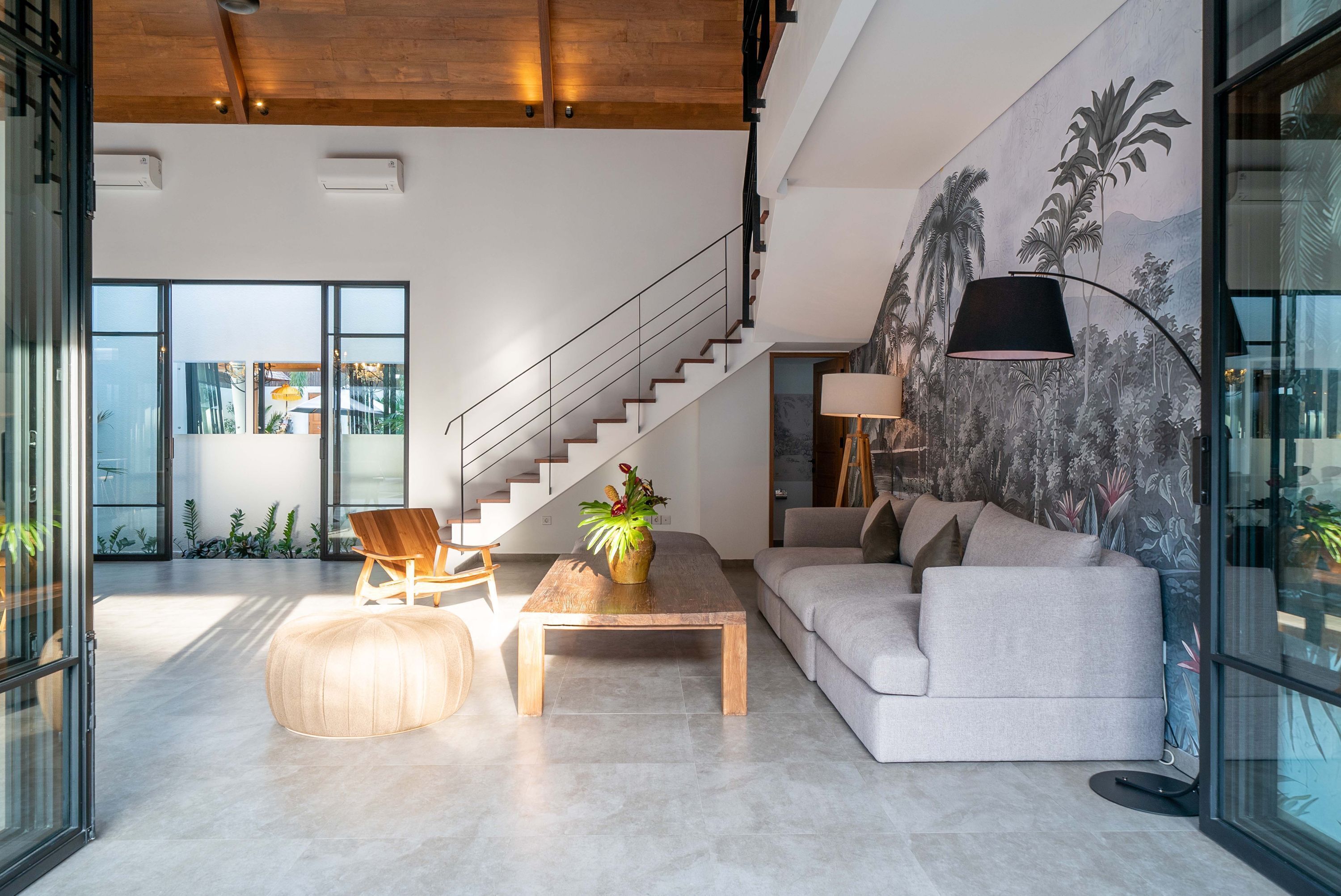 A modern living room with a staircase, a sofa, a coffee table, and a chair.