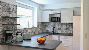 A modern kitchen with a central island, a microwave, and a coffee maker. - Romantic mill arbor "At the foot of the Staffelberg" (Bad Staffelstein)