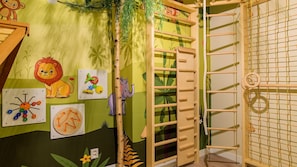 A child's playroom with a jungle theme, including a climbing ladder, educational toys, and a wall with animal illustrations.