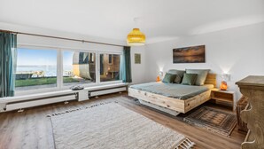 A bedroom with a large window, a bed, a wooden headboard, a nightstand, and a lamp. - Nice home in Wunstorf/Steinhuder (Wunstorf/Steinhuder)