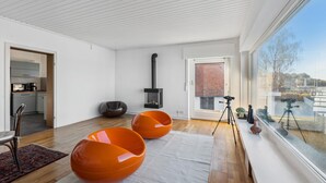 A modern living room with a large window, a fireplace, and a kitchen area visible through an open door. - Nice home in Wunstorf/Steinhuder (Wunstorf/Steinhuder)