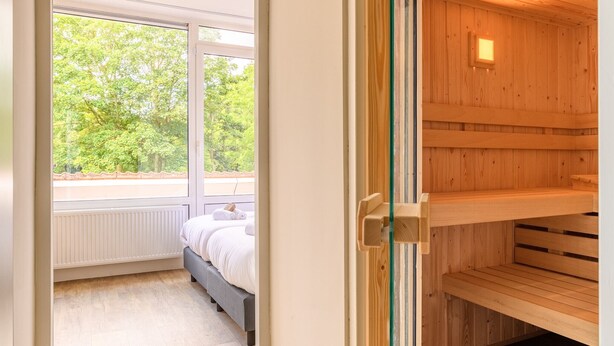 A room with a bed, a window, and a sauna. - 4-person apartment with wellness (Hageweg 'T Centrum)
