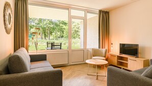 A modern living room with a sofa, a TV, and a table. - 4-person apartment with wellness (Hageweg 'T Centrum)