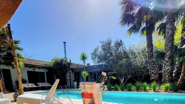 A wooden table with a tray of strawberries and bananas, a bottle of champagne, and two glasses of wine by a poolside. - HOUSE "L'OLIVETTE" jacuzzi, heated pool, billiards, table soccer, 7KM from Nîmes  (LANGLADE)