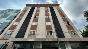 A multi-story building with a modern architectural design, featuring a mix of window sizes and a central vertical element.