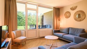 Ein Wohnzimmer mit einer Couch, Sesseln, einem Fernseher und einem Tisch.