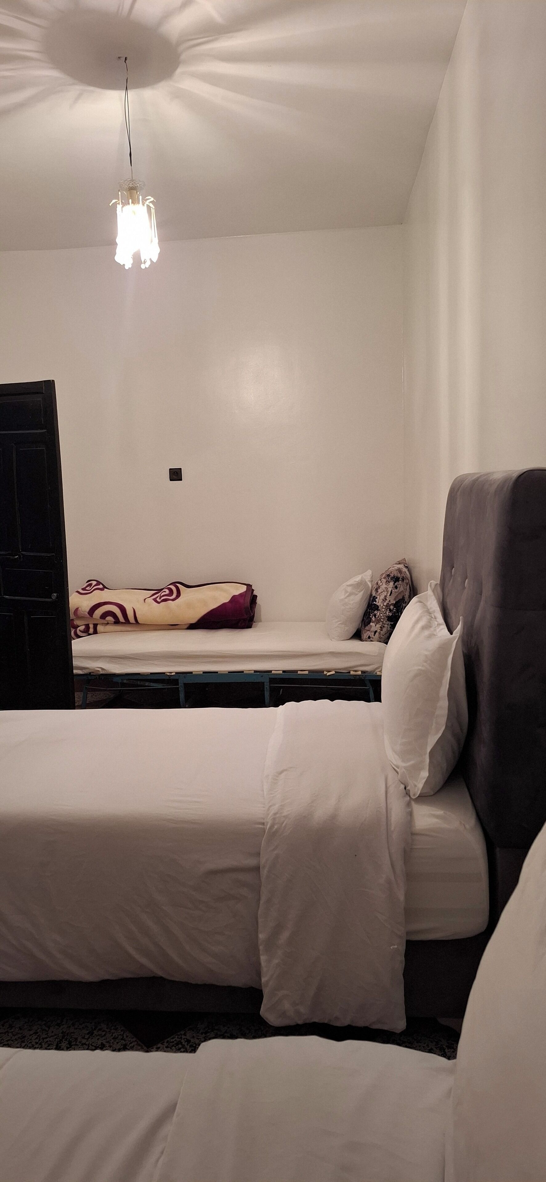 Una habitación con cama, una silla y una lámpara colgante.